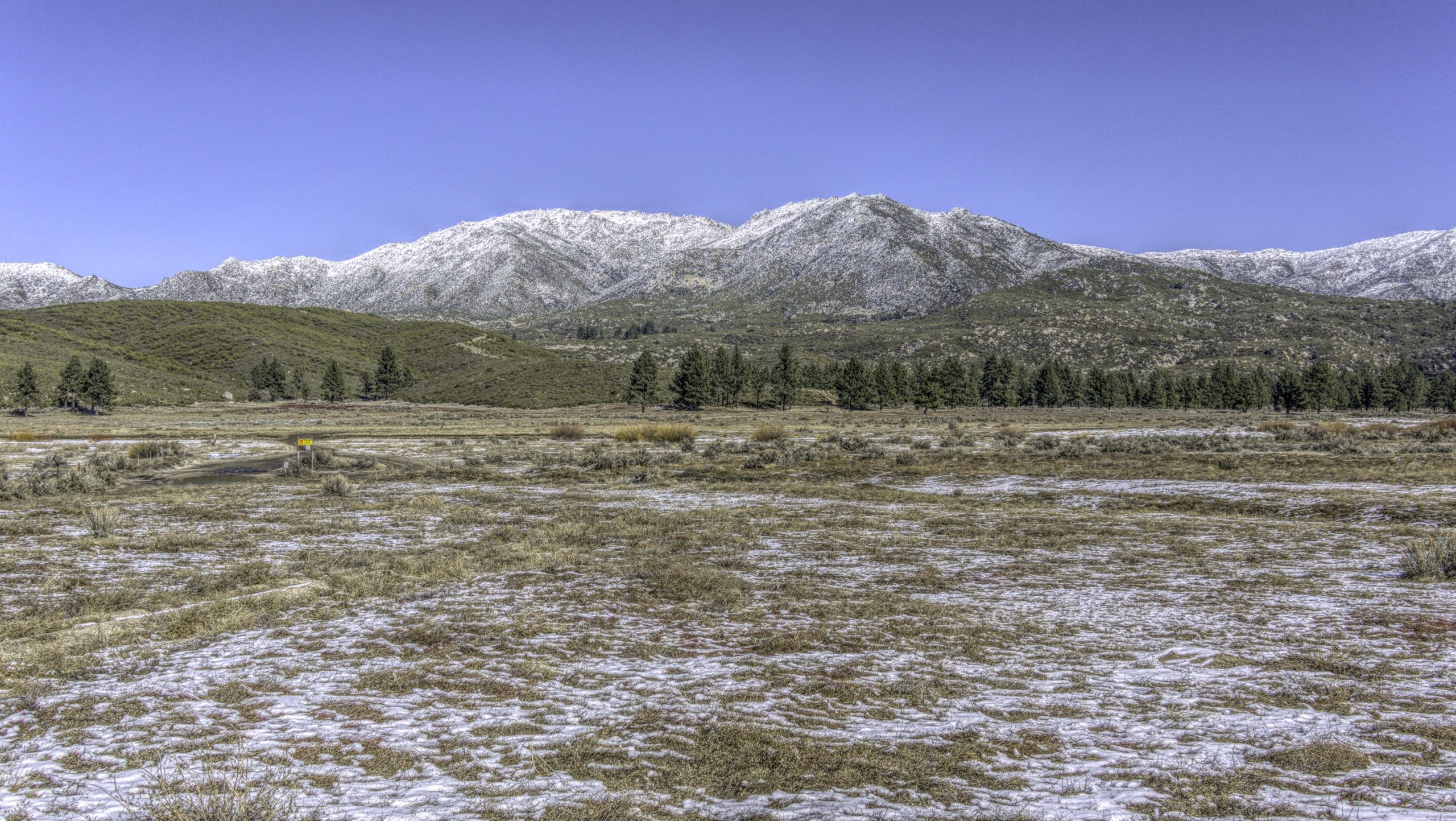 A view of the San Jacinto Mountains with a large field in front with some snow on it