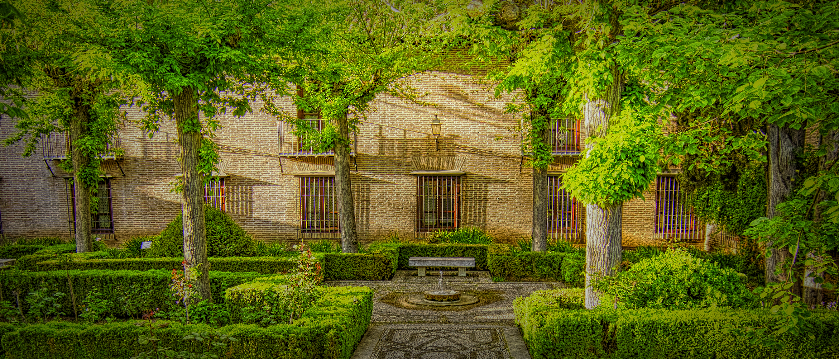Bench and fountain in a garden of green at the Alhambra in Granada, Spain