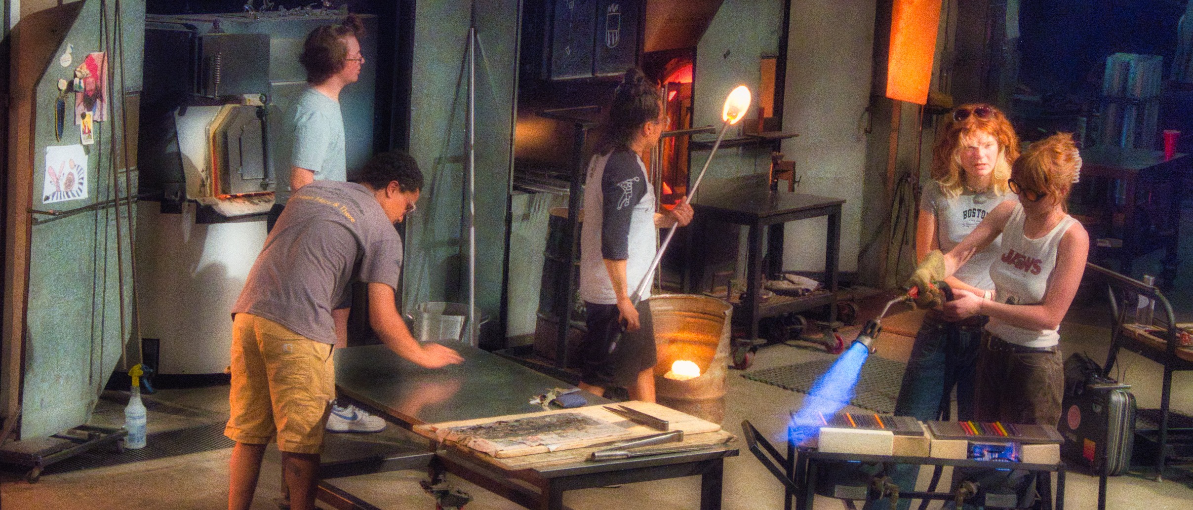 Various people working in a hot room to create glass objects