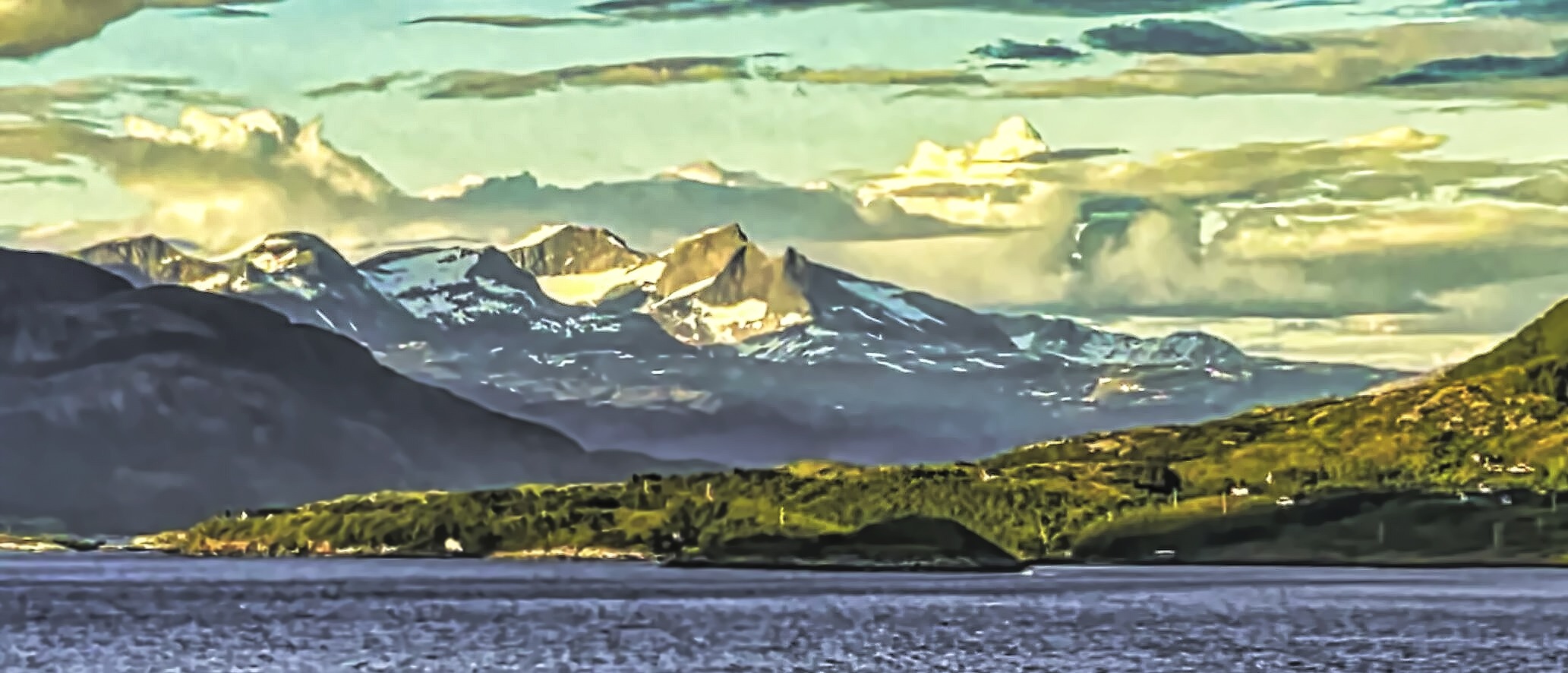 Snow on th mountain peaks along the coast of Norway.