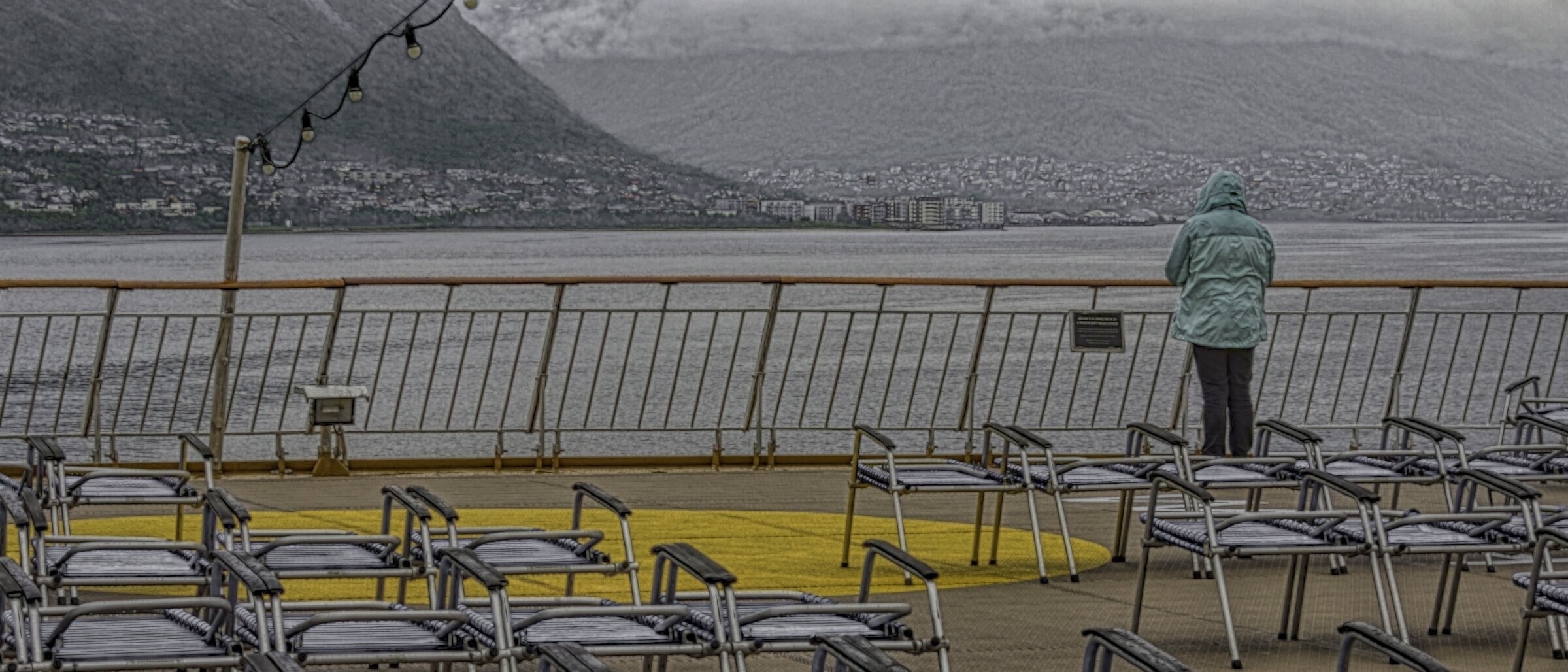 Woman looking over the rail of the cruise ship at the city of Tromsø, Norway